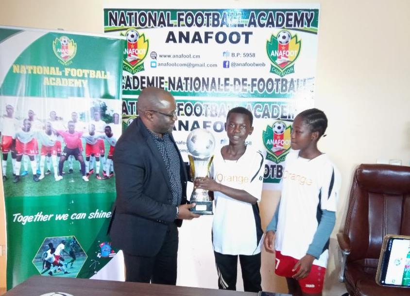 Yaoundé, le 20 avril 2023. Le capitaine de l'équipe de l'Anafoot prfésentant le trophée de la CWC Cup U13 au DG Enow Ngachu